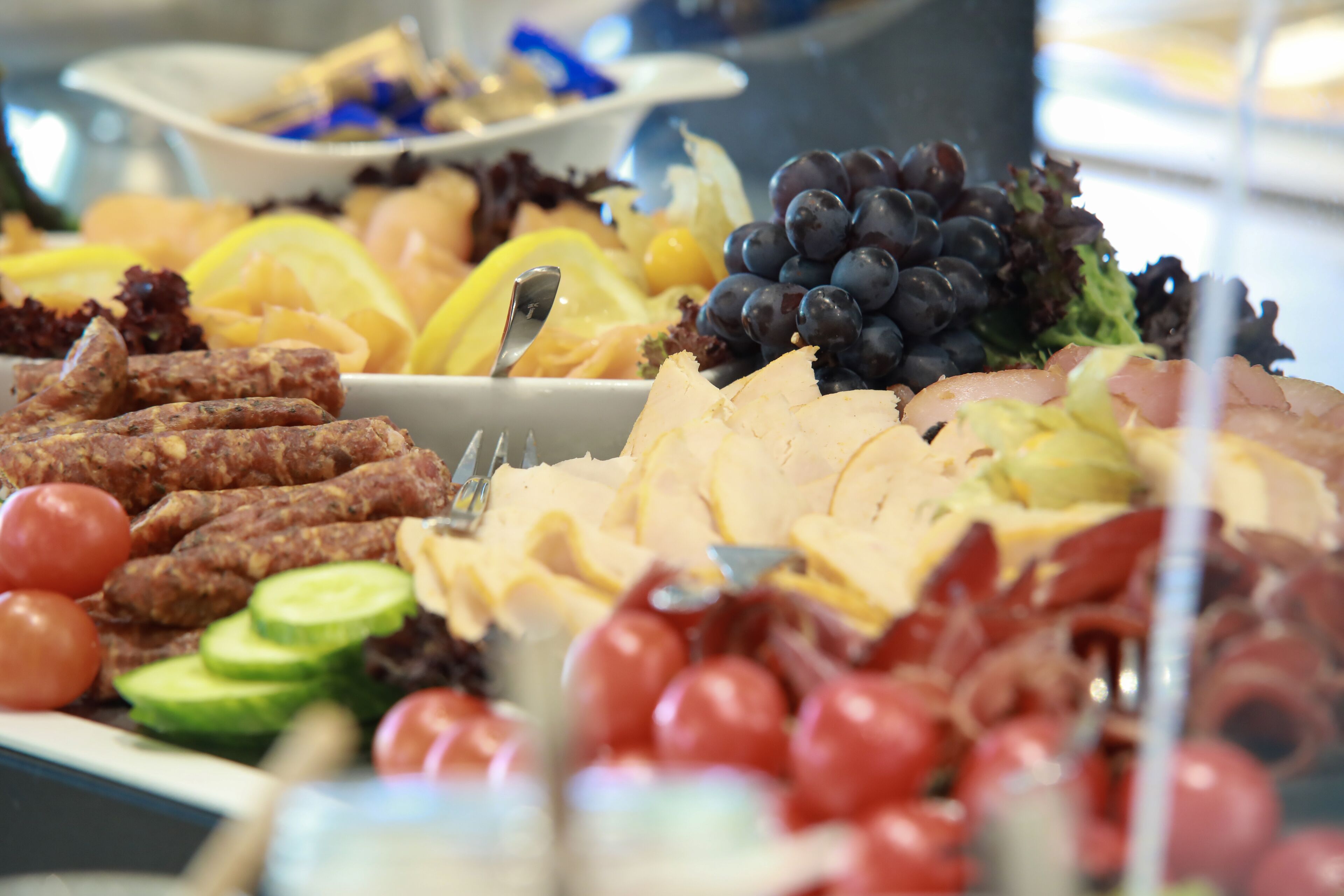 A buffet with various food items including meats, cheeses, fruits, and vegetables.