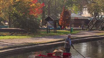 A narrow canal with a boat carrying wooden chairs and a red cover.