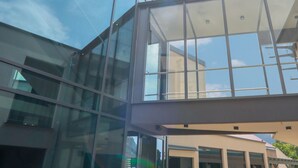 A modern building with large glass windows and a covered entrance area. - SPREE. Hotel am Hafen (Lübbenau/Spreewald)