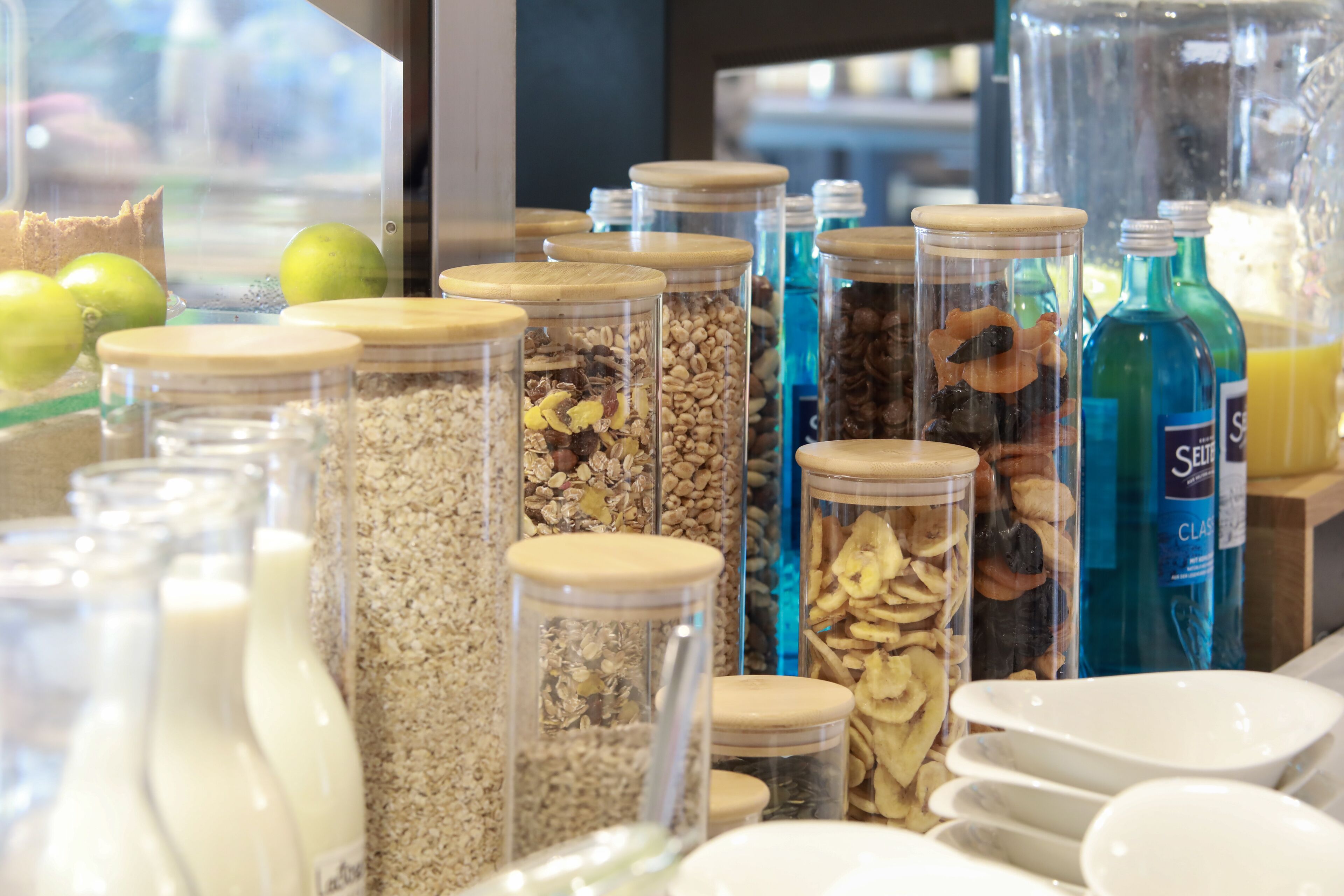 A variety of food items in glass jars with wooden lids, arranged on a counter.