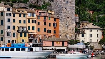 A waterfront town with historic buildings, including a castle-like tower, and a boat docked at the harbor.