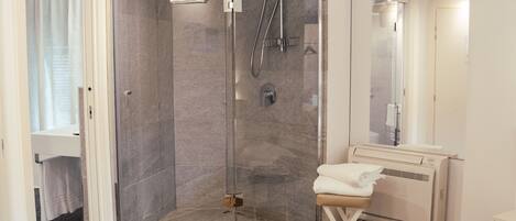 Un baño moderno con cabina de ducha de vidrio, lavamanos blanco y barra para toallas.