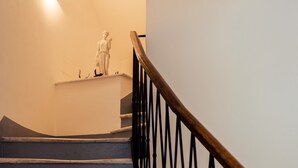 A staircase with a wooden handrail and black balusters, leading to a landing with a white wall and a light fixture. - Torre A Mare Porto Venere (Portovenere)