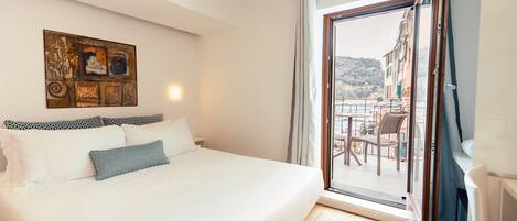Un dormitorio con una cama, un cuadro en la pared y vistas a un balcón con mobiliario exterior.