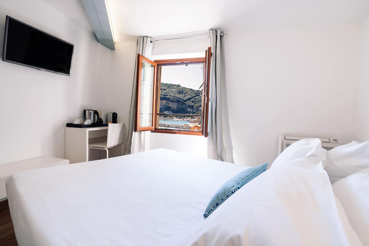Une chambre d’hôtel équipée d’un lit, d’un bureau, d’une télévision et d’une fenêtre donnant sur une montagne et une piscine.