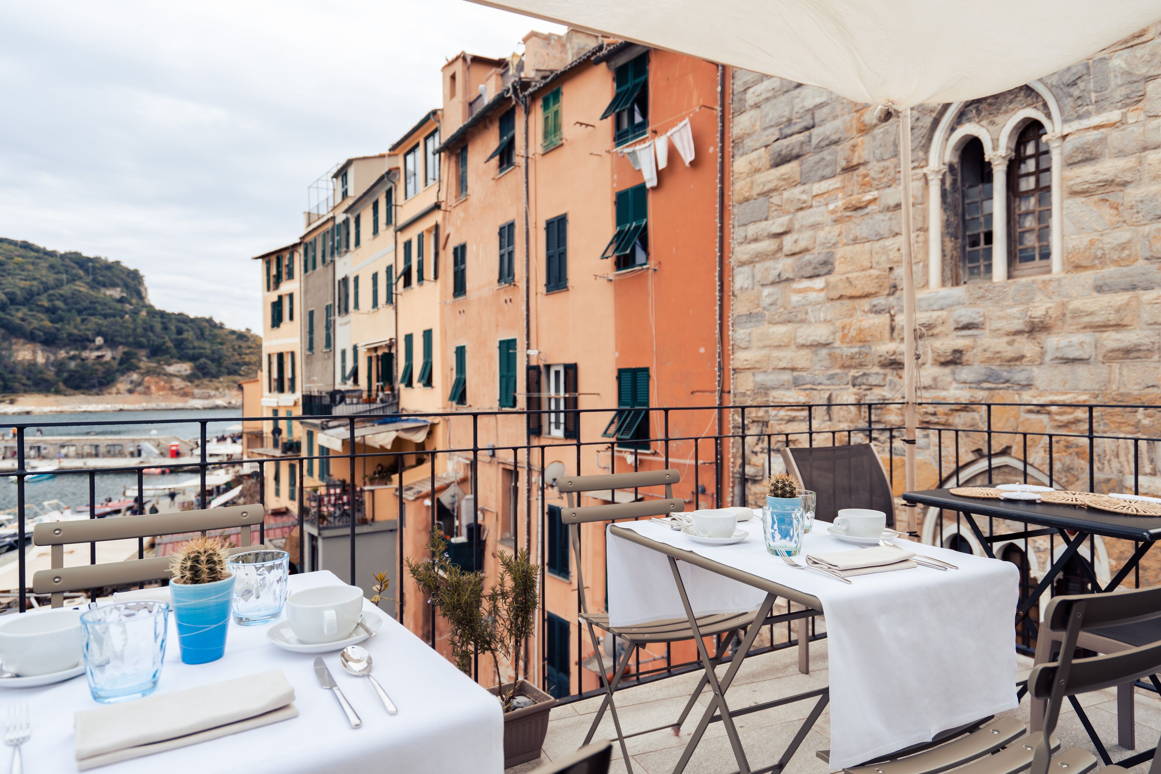 Una terraza con mesas dispuestas para comer, con vistas a la costa, edificios y al mar.