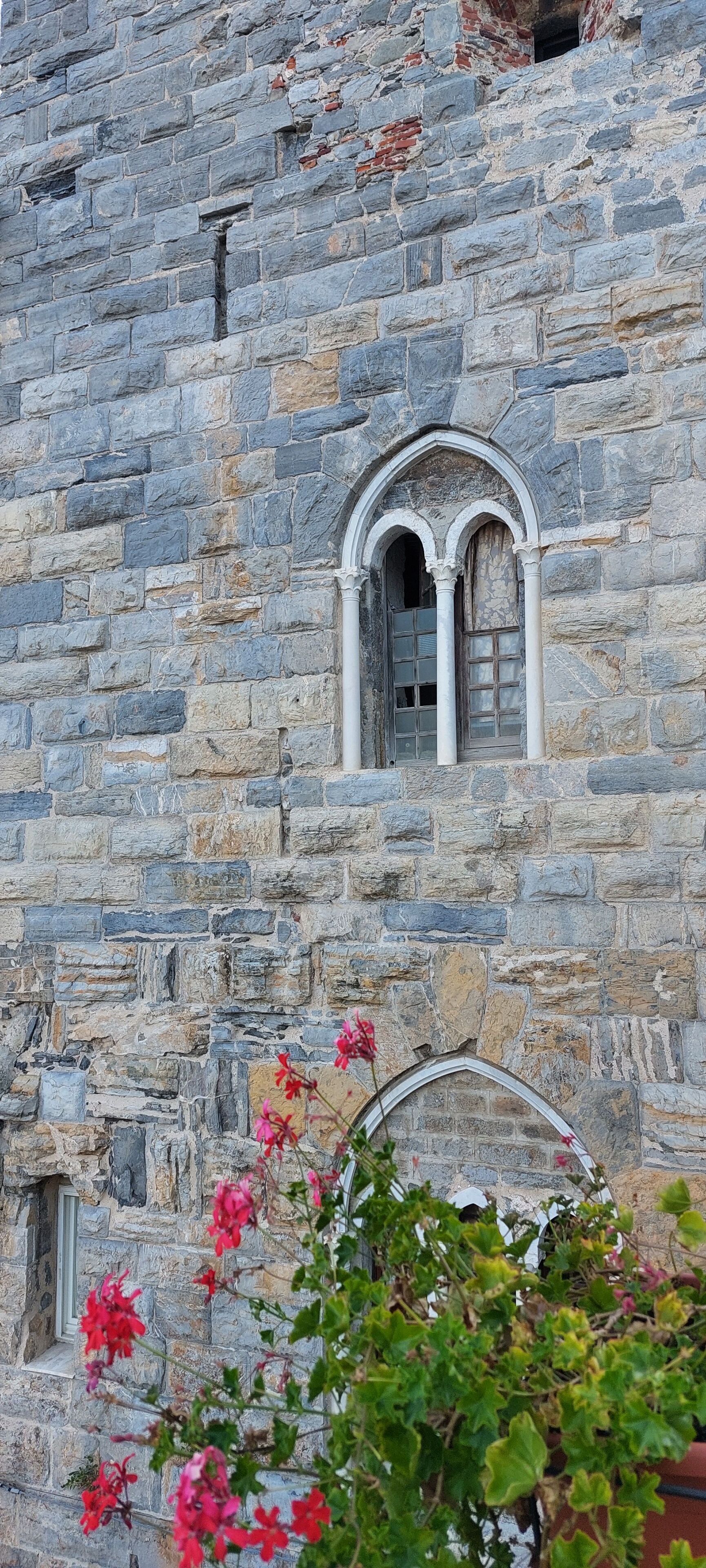 A stone building with a window featuring an arched design.