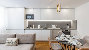 Una cocina moderna con armarios blancos, una mesa de comedor con platos y tazones, y un sofá con un cojín que dice 'Thankful'.