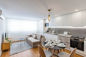 A modern kitchen with a dining area, a sofa, and a small side table. - Apartment in the city center—modern, new, and cozy—with 2 bedrooms and 2 bathrooms (Porto)