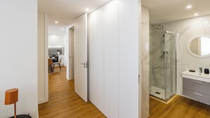 Un baño moderno con cabina de ducha de vidrio, lavabo de mármol y tocador blanco.