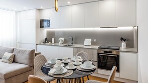 Una cocina moderna con armarios blancos, una mesa de comedor con platos y tazas, y un sofá con un cojín.