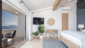 Una camera da letto moderna con un balcone, una TV, una scrivania e un letto.