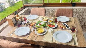 A dining table set with plates, cutlery, and various dishes, surrounded by cushioned chairs. - Sirius Otel Pamukkale (Denizli)