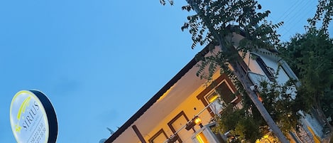 A hotel with a signboard, multiple balconies, and outdoor seating areas.