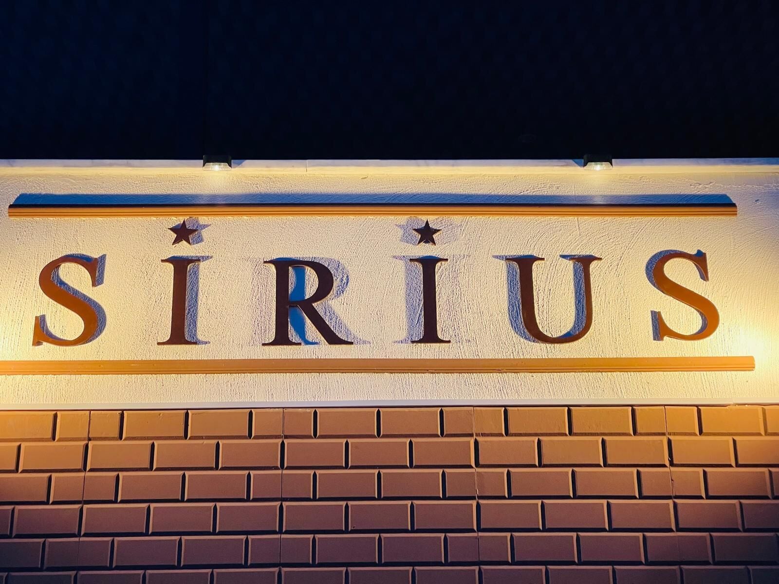 A sign with the word 'SIRIUS' in large, bold letters on a brick wall.