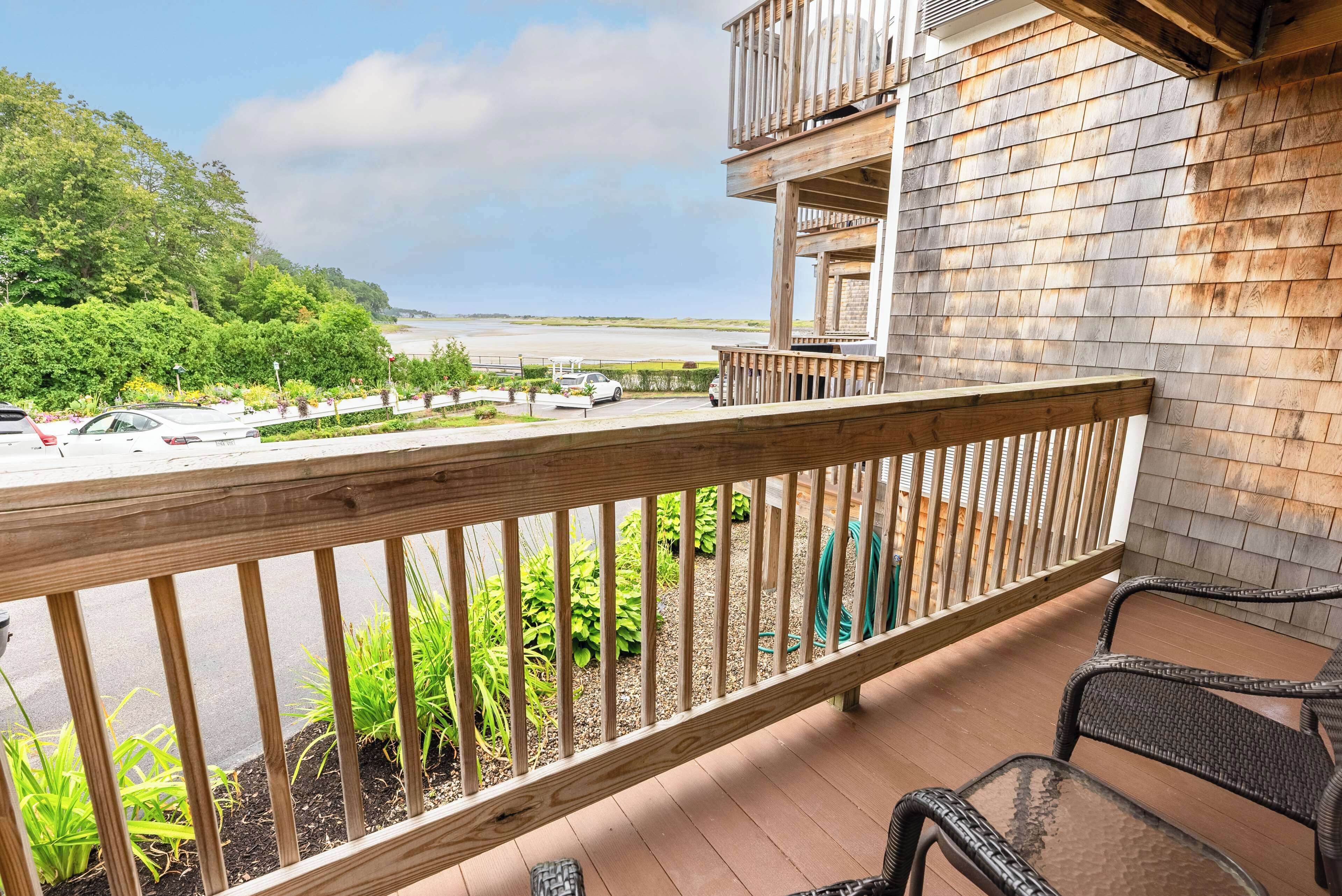 A wooden balcony with a view of a parking lot and beach.