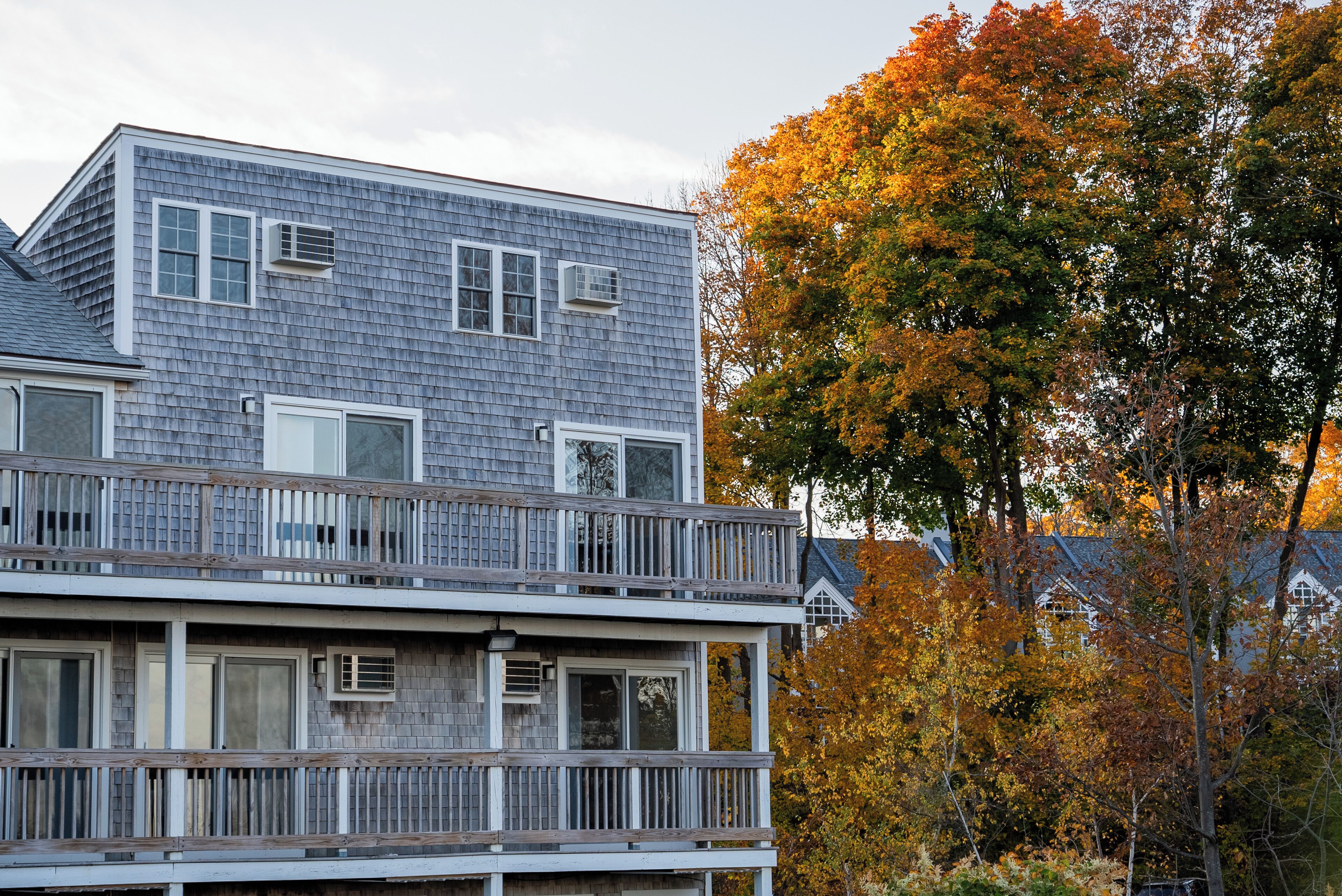 A two-story building with a balcony, multiple windows, and an air conditioning unit.