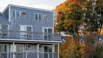 A two-story building with a balcony, multiple windows, and an air conditioning unit.