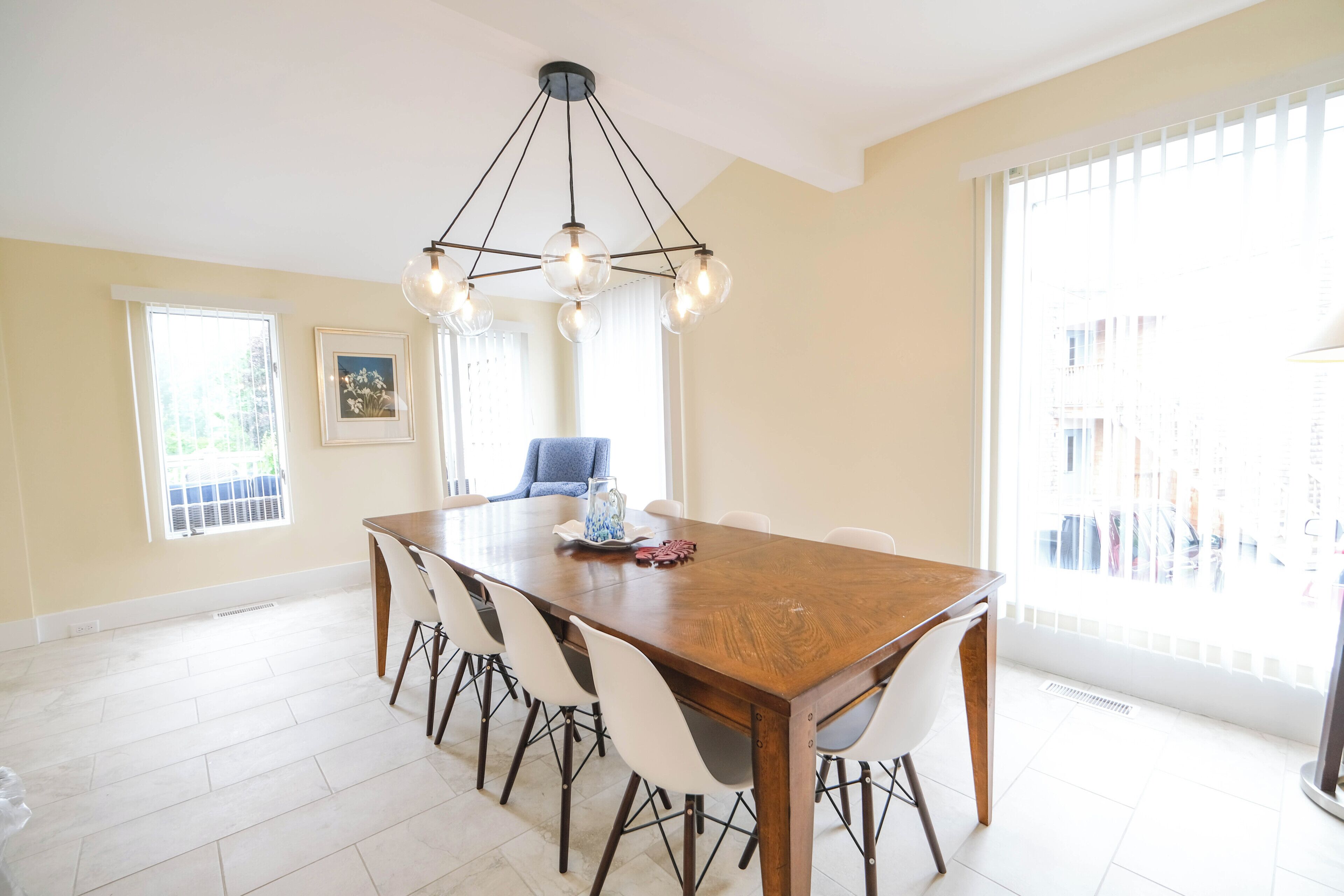 Un espace repas avec une table en bois, des chaises blanches et un lustre moderne.