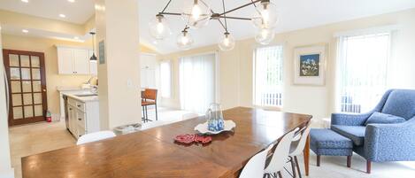 A spacious dining area with a wooden table, white chairs, and a blue patterned armchair.