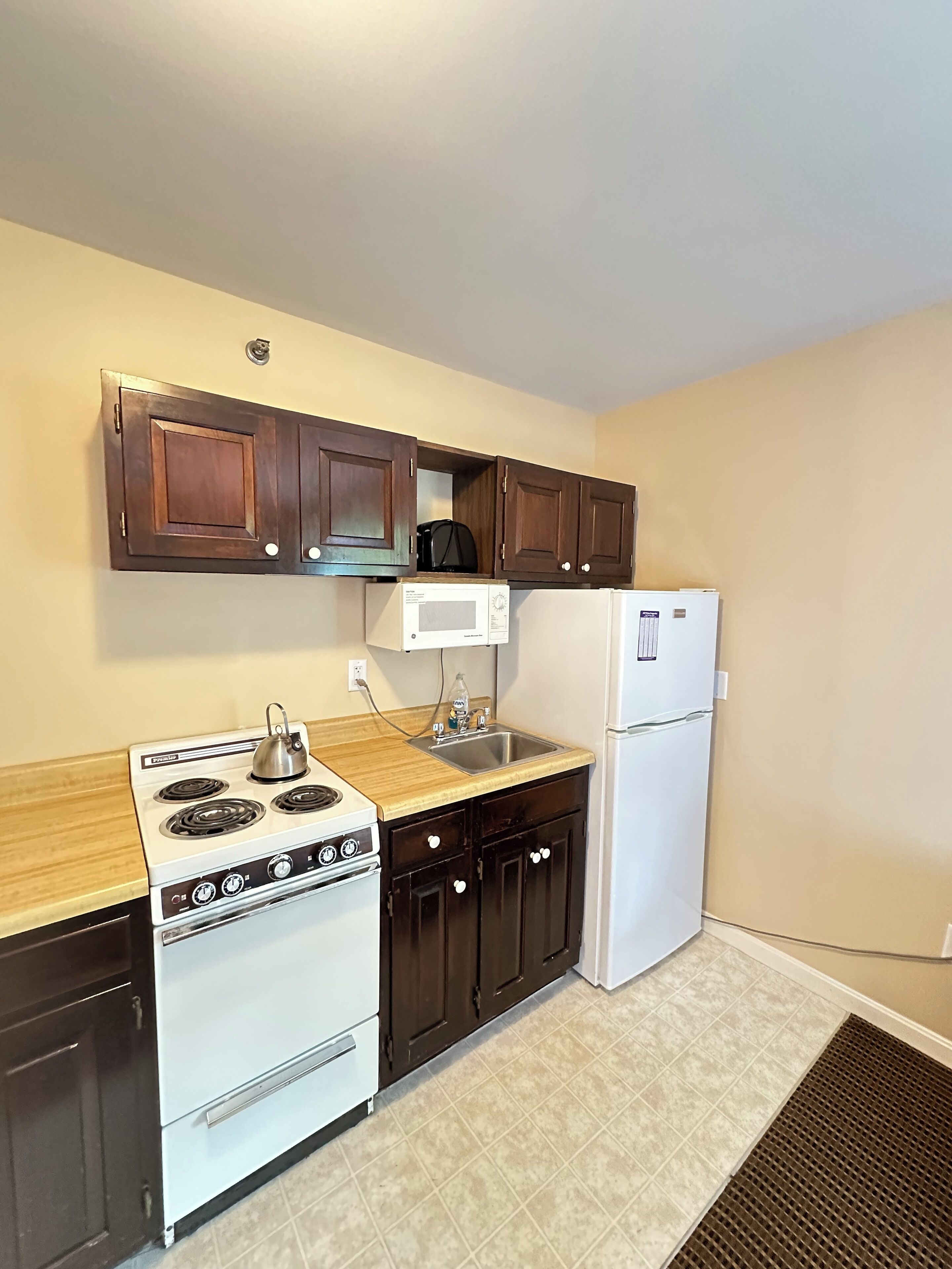A compact kitchen with a stove, microwave, and refrigerator.