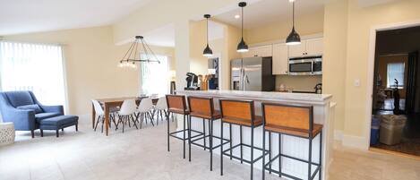 A modern kitchen with a central island, bar stools, and contemporary appliances.