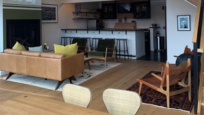 A modern living space with a sofa, chairs, a dining table, a kitchen, and a staircase. - Hotel Dylan (Woodstock)