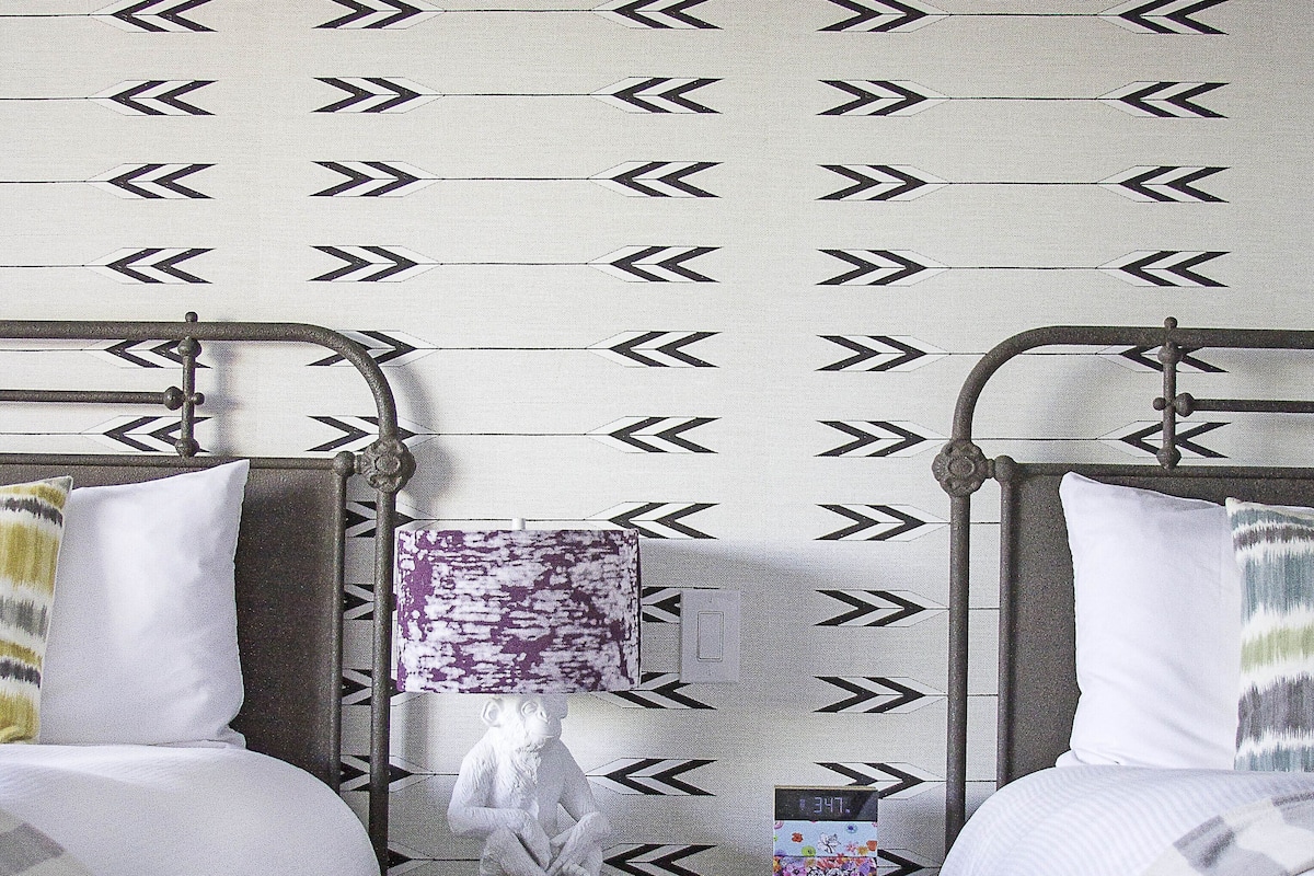 A bedroom with two metal beds, a nightstand, a lamp, and a digital clock.