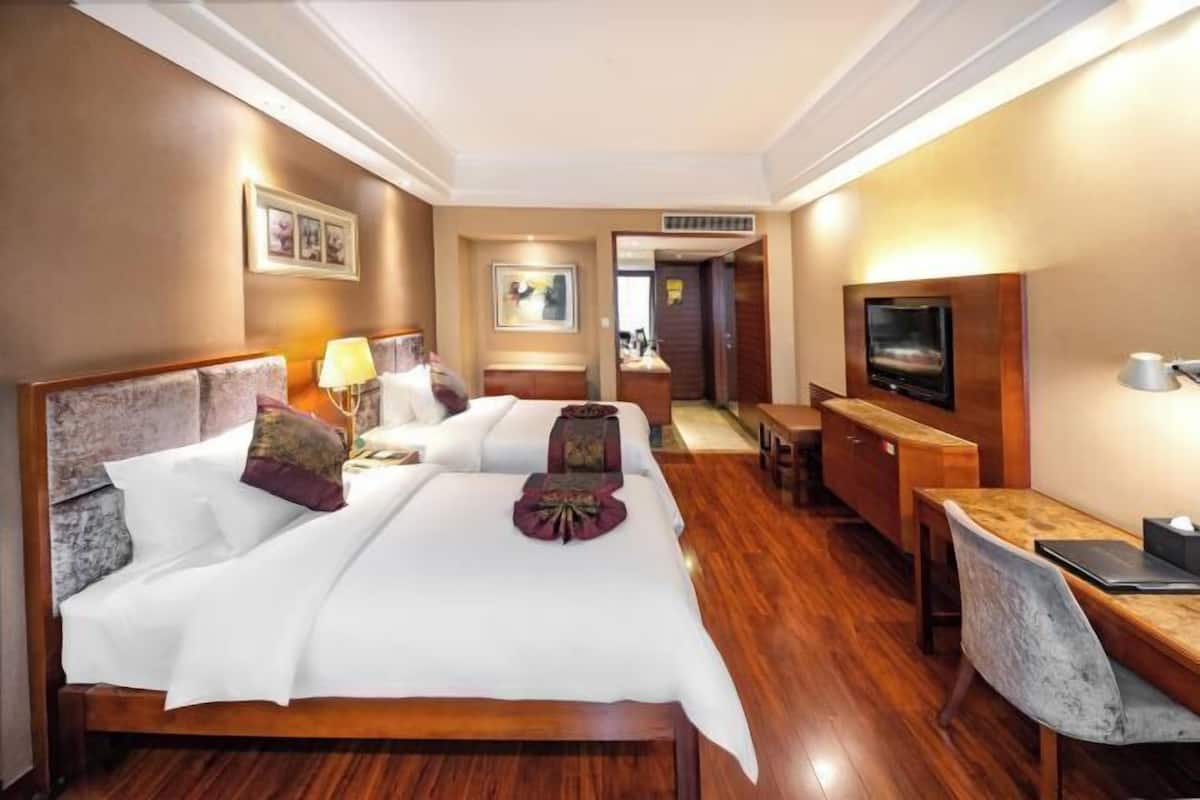 Una habitación de hotel con una cama grande, un escritorio, un televisor y un espejo.