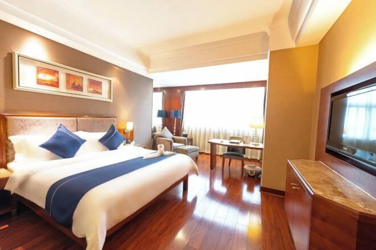 Una habitación de hotel con una cama grande, un escritorio, un televisor y una ventana.