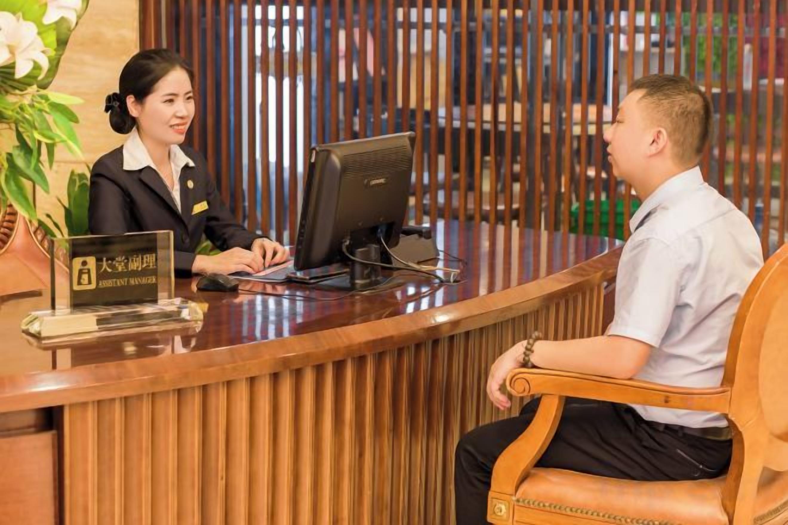 A reception desk with a computer, a sign with Chinese characters, and a wooden partition.