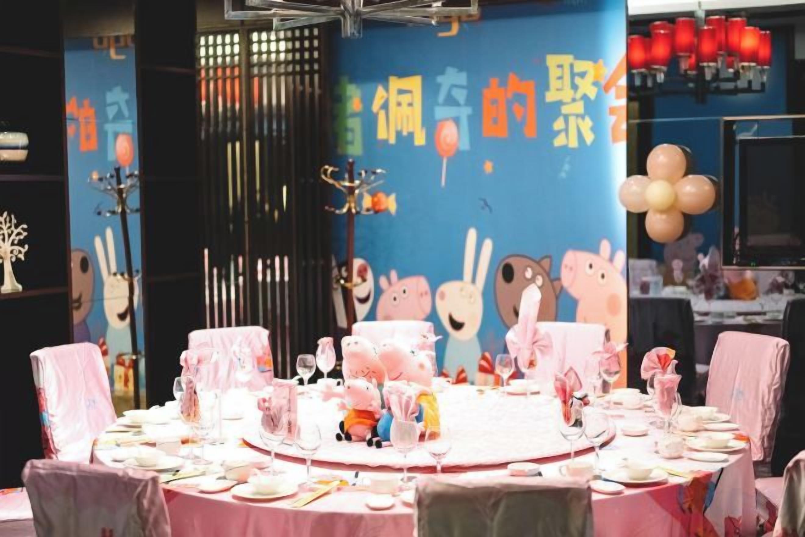 A dining area with round tables set for a meal, decorated with pink tablecloths and various dishes.