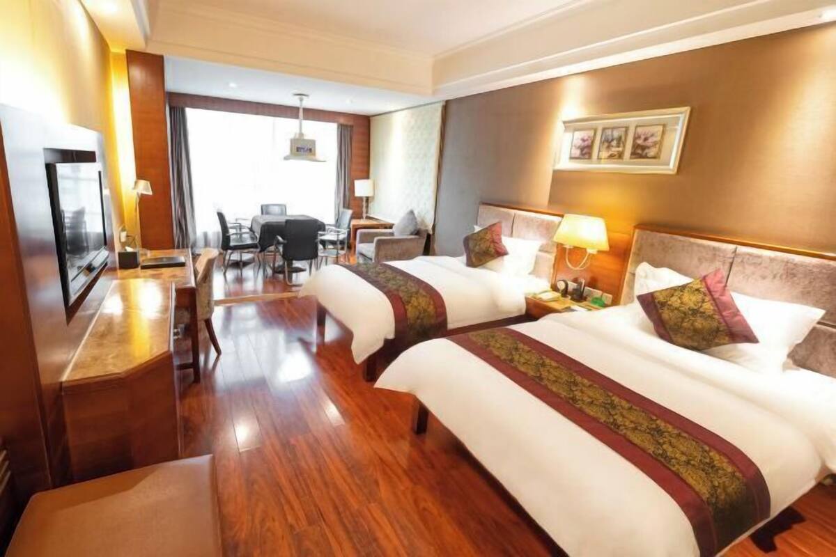 Una habitación de hotel con dos camas, un escritorio, un televisor y un comedor.