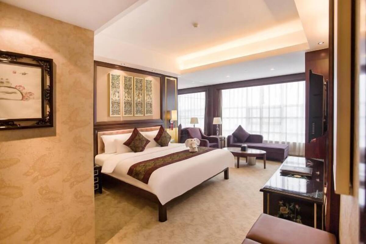 Una habitación de hotel con una cama grande, un escritorio, una silla y un televisor.
