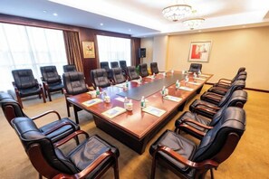 Un salón de conferencias con una larga mesa, varias sillas y una araña.