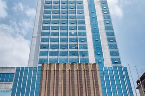 A tall building with a modern design, featuring a series of windows and a prominent entrance area. - Shenlong New World Hotel (Leiyang)