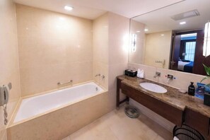 A modern bathroom with a bathtub, a sink, and a large mirror. - Shenlong New World Hotel (Leiyang)
