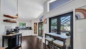 Eine moderne Küche mit dunklem Holzboden, weißen Schränken und einer Bar mit Hockern.