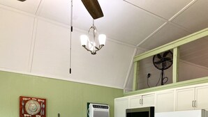 A kitchen with a central island, bar stools, a microwave, a refrigerator, and a ceiling fan. - The Dogwood at Hamilton Cove ~ Peaceful Lakefront Cabin on Lake Hamilton (Royal)