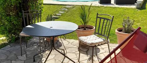 A patio with a table and chairs, a pool, and a garden.