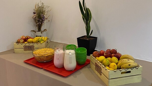 A buffet table with various fruits, a potted plant, and a vase of dried flowers. - Hotel Delfin (Mar del Plata)