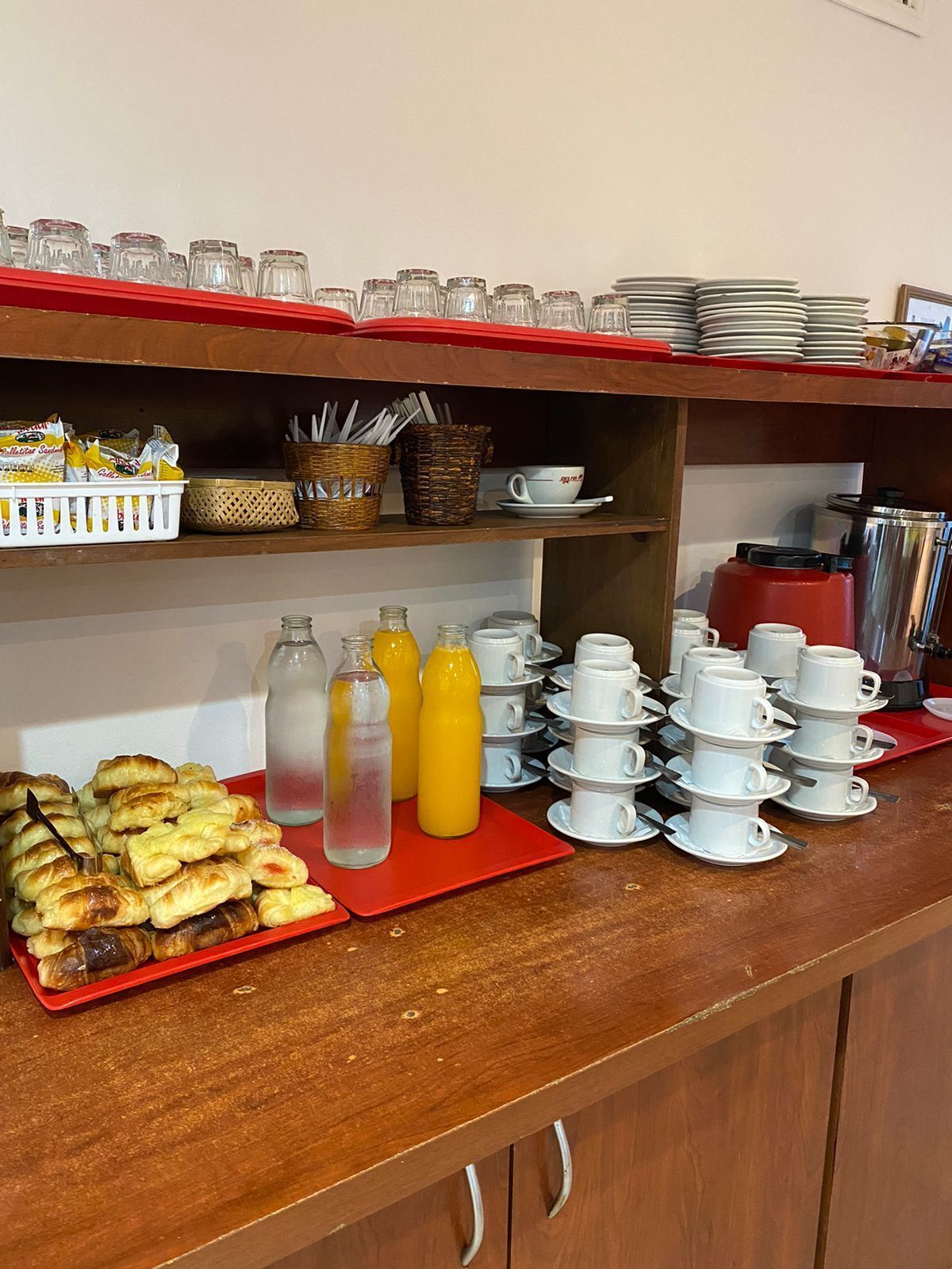 Morgenmadsbuffet med kager, juice og stablede kopper og tallerkener.