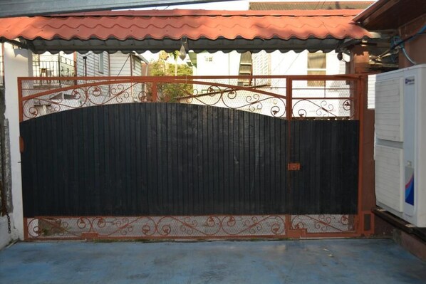 A gated entrance with a decorative metal gate and a corrugated metal roof above.