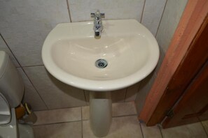 A bathroom with a white sink, a toilet, and a wooden door.