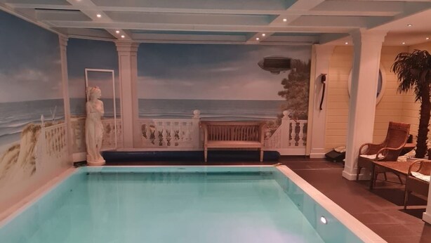 A swimming pool with a view of the ocean, a statue, and a bench.