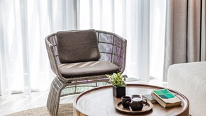 A modern living room with a wicker chair, a round wooden coffee table, and a hanging light fixture. - Vivir Jiaoxi Hotel (Jiaoxi)