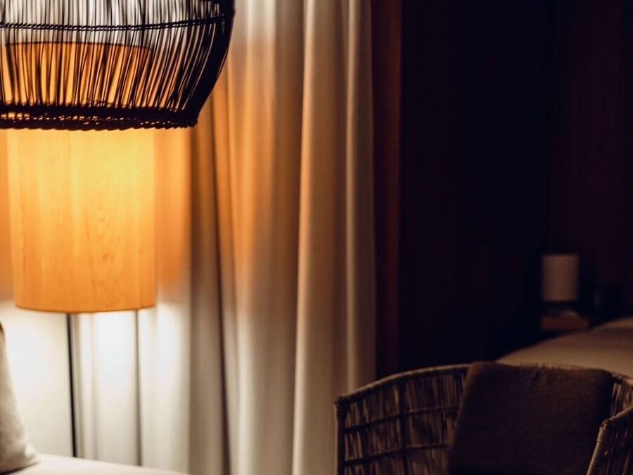 Una habitación acogedora con una mesa de centro de madera, una silla de mimbre, un sofá y una lámpara.