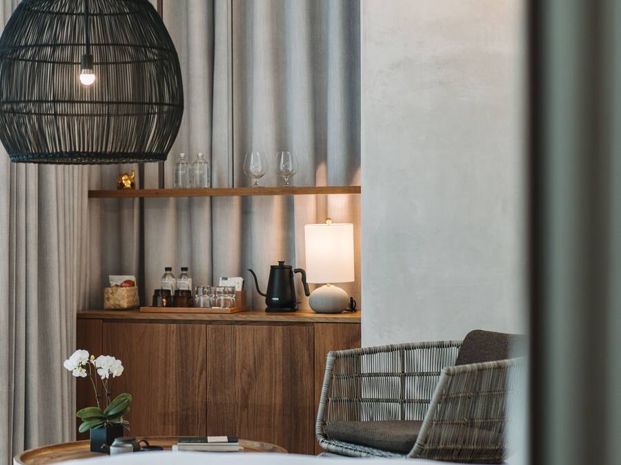 A cozy room with a wooden counter, a hanging light fixture, and a comfortable chair.