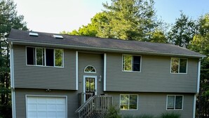 A two-story house with a garage, a front porch, and a gravel driveway. - Great Home in South County, Close to Narraganstt and Newport &.08 miles from URI (South Kingstown)