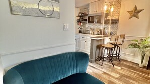 A living room with a blue sofa, a kitchen in the background, and a star decoration on the wall. - Historic Love, Modern Appeal C (Haines City)
